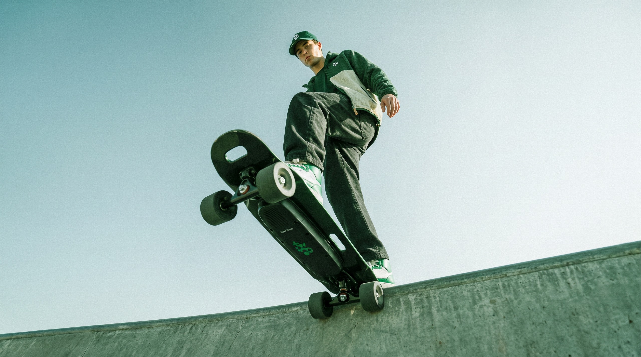 Twingomania Renault : un skateur en tenue verte avec un skateboard électrique, photographié en contre-plongée.